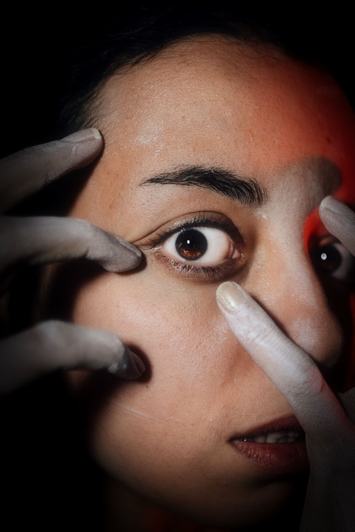 Close-up of a performer framing her eye with powdered fingers